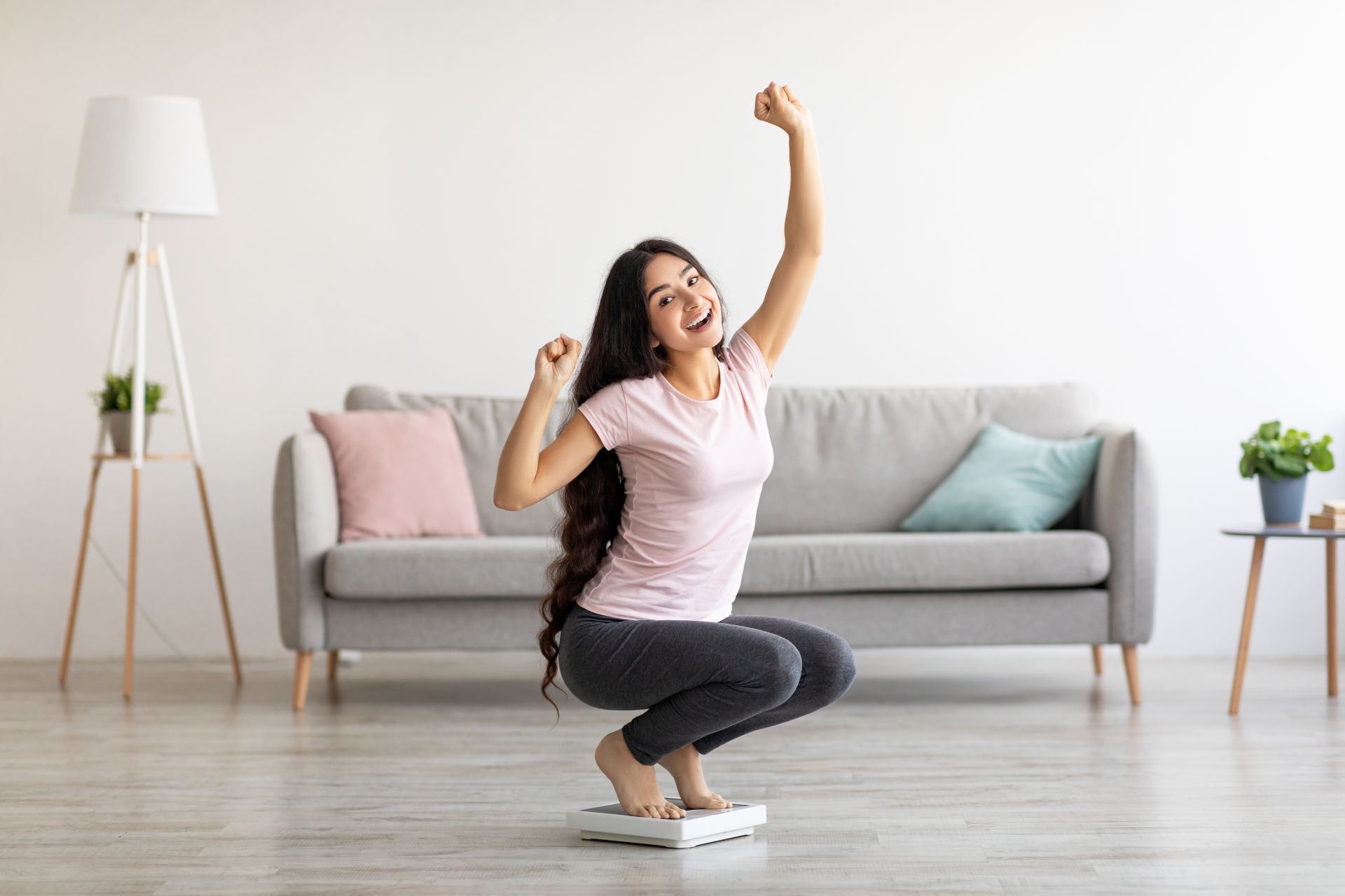 Cómo motivarse: 5 trucos de eficacia probada Uśmiechnięta kobieta na wagach na tle kanapy